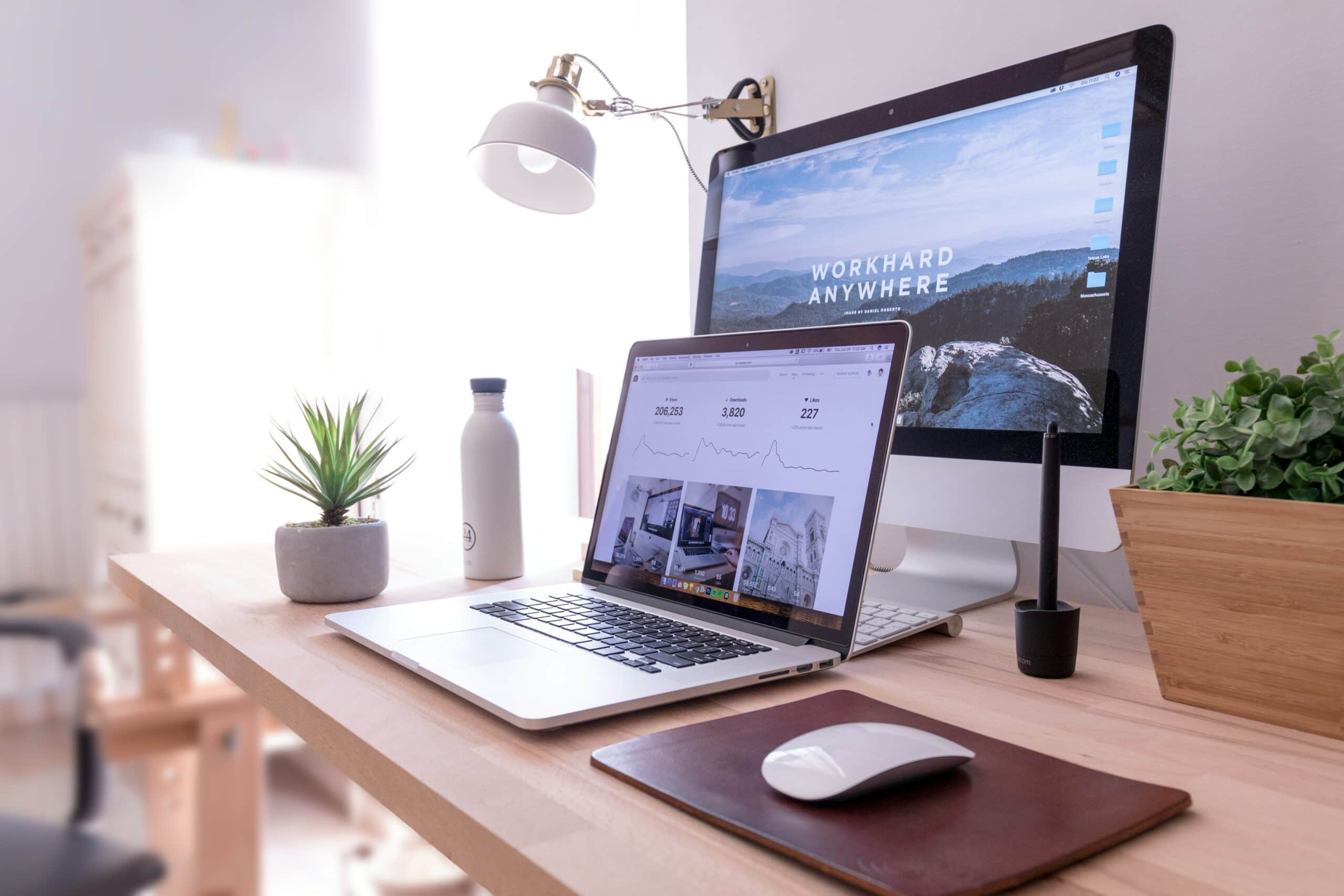 A desk with no one sitting at it that displays a mountain top and the words "workhard anywhere".